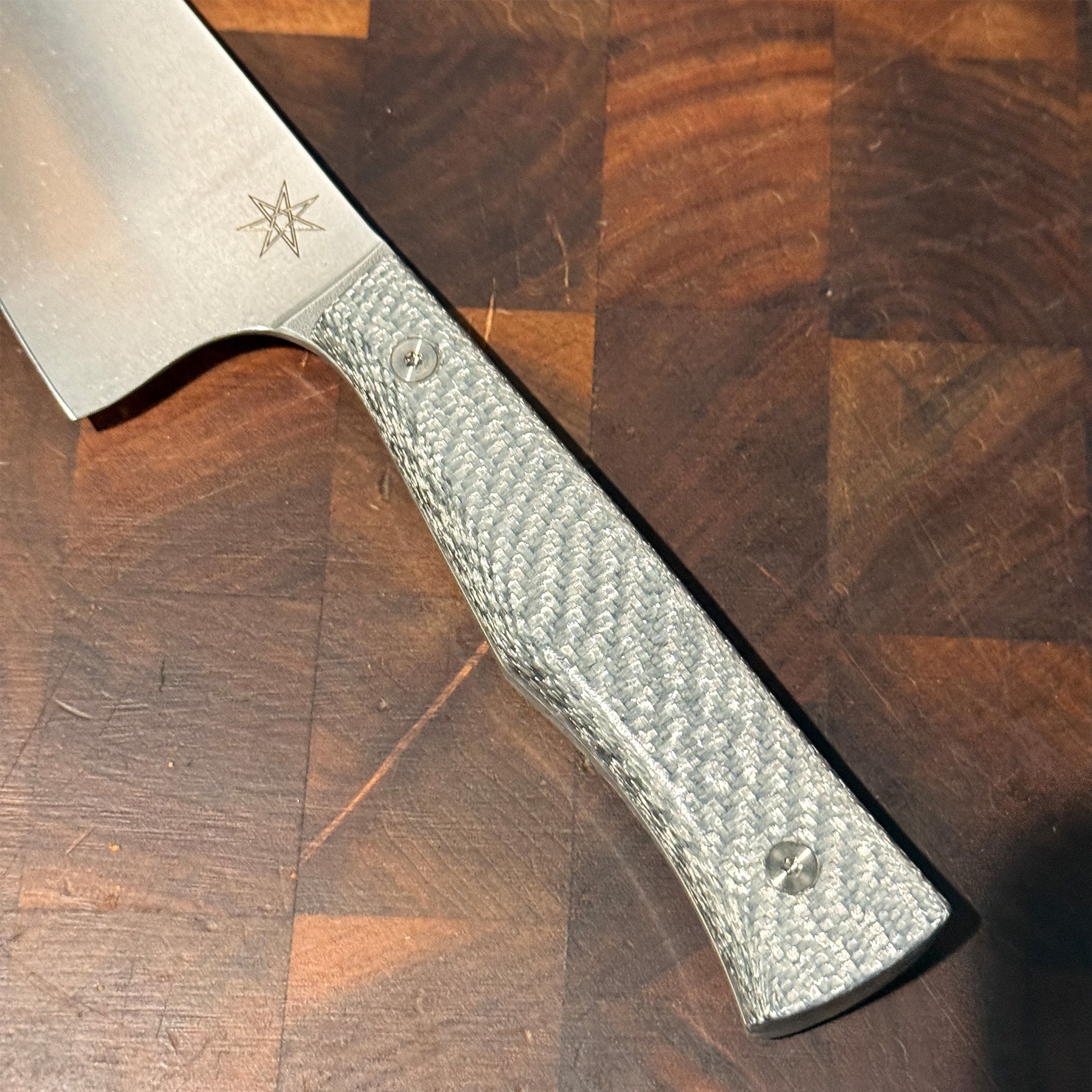 Chef Knife with a textured silver carbon fiber handle on a wooden surface