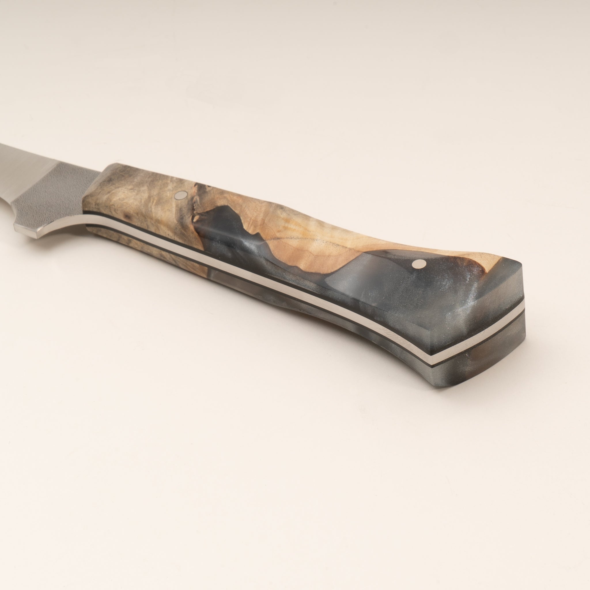 Close-up photo of a curved boning knife handle with wood and resin handle on a white background.