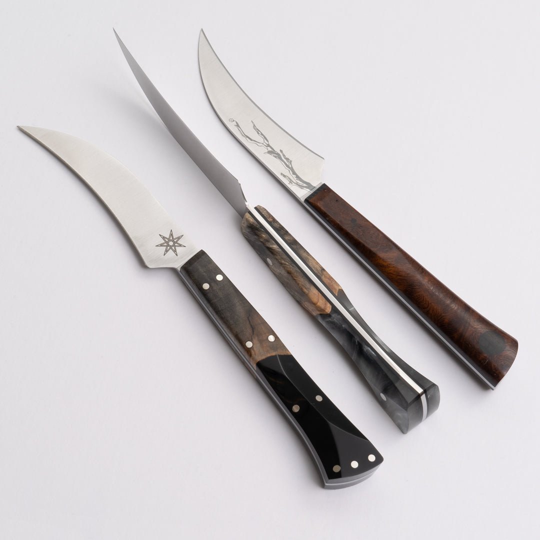 Three bird's beak knives with different handles on a white background.