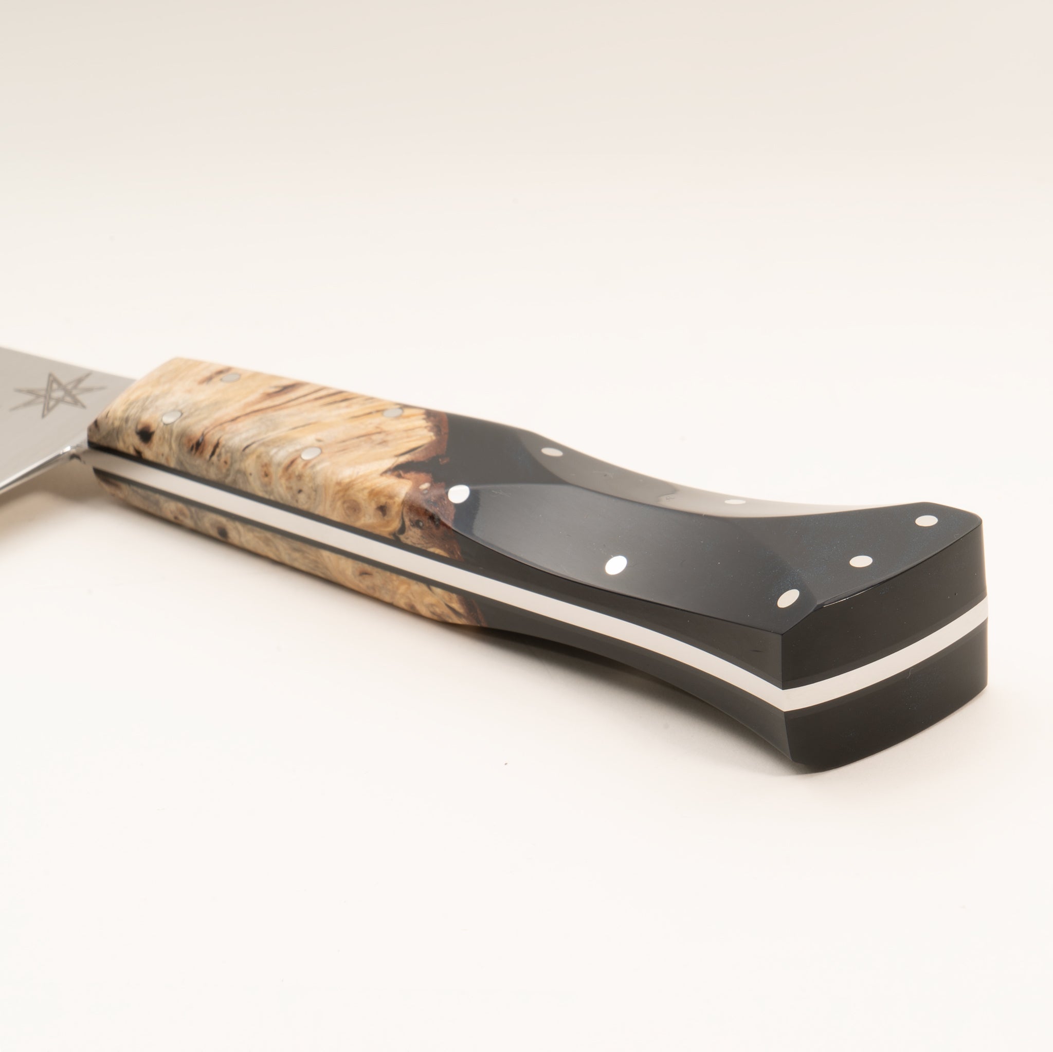 Close-up of a kitchen chef knife handle made from wood and black resin, on a white background.