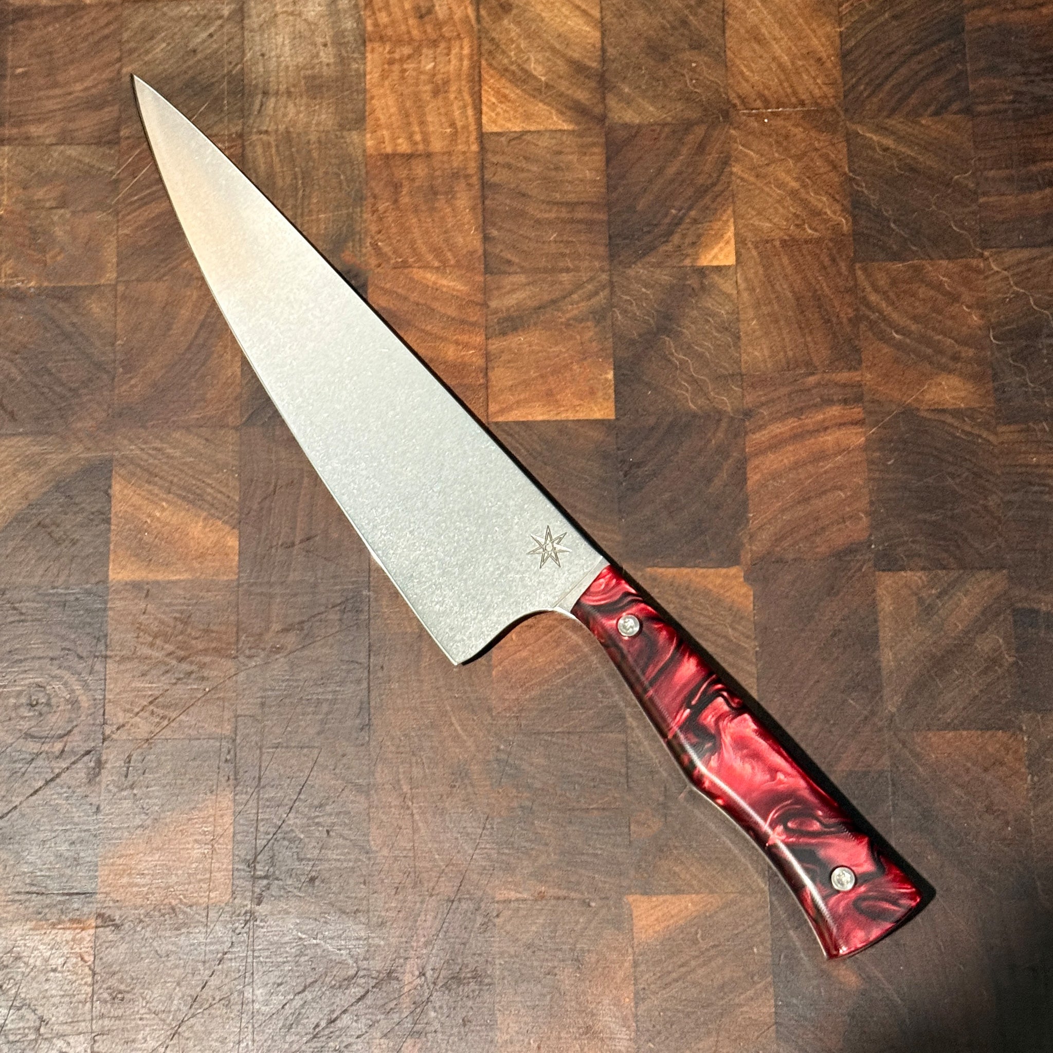 Knife with a red handle on a wooden cutting board
