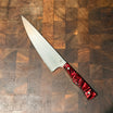 Knife with a red handle on a wooden cutting board